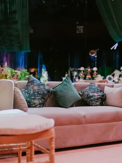 A close-up of the plush lounge sofas, adorned with custom floral and solid green cushions, providing a comfortable and stylish seating option for guests.
