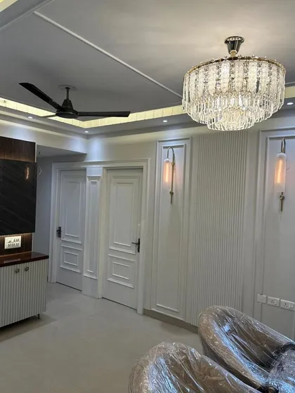 This living area showcases our expertise in creating dramatic lighting and wall textures. A grand crystal chandelier serves as the centerpiece, complemented by vertical fluted panels and elegant wall sconces. The design creates a sense of height and luxury.