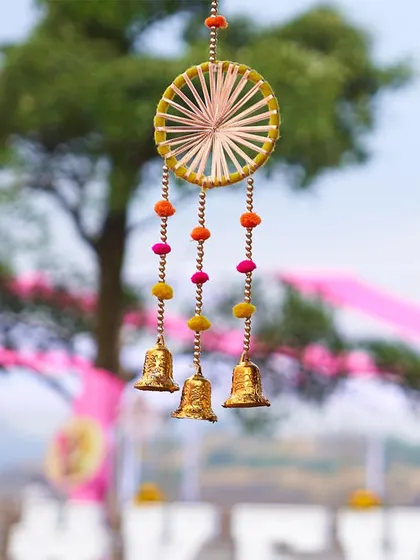 A close-up of a colorful dreamcatcher with hanging bells, used as a decorative element in a vibrant Mehendi or Haldi setup.