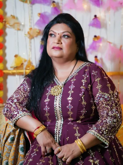 A pretty and dramatic look for a festive event. The makeup is glamorous, with a focus on the eyes, and complements her embroidered purple outfit.