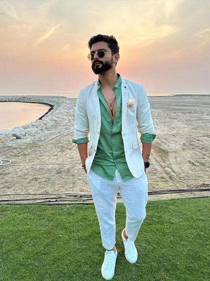 A smart, beach-formal look with a white blazer over a green shirt, perfect for a sunset event.