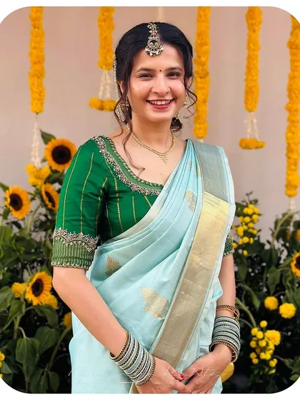 A close-up of our happy client in her custom ensemble. The detailed embroidery on the green blouse beautifully contrasts with the soft hue of the blue silk saree.