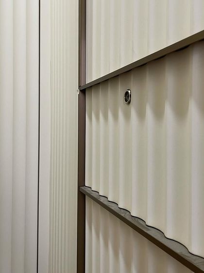 A close-up shot of the curved fluting detail on the wardrobe doors. This textural element adds a layer of sophistication to the closet design.