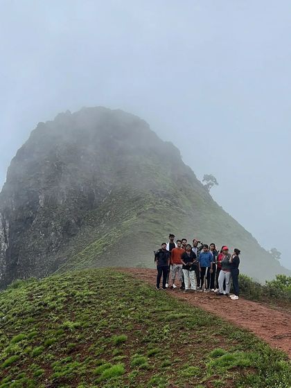 The group posing on a ridge with a fog-covered peak behind them.