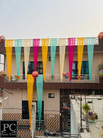 A different perspective of the decorated house, showcasing the beautiful arrangement of drapes and umbrellas against the daytime sky.
