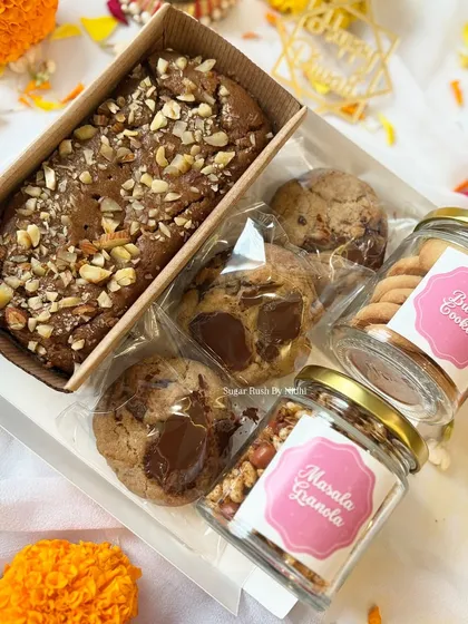 A beautiful hamper for Diwali, containing a tea cake, chocolate chunk cookies, and jars of masala granola and butter cookies.