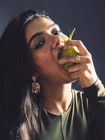 A close-up of the model biting a pear, creating a powerful and slightly aggressive mood that challenges typical beauty standards.