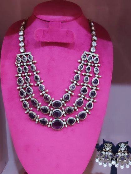 A three-layered necklace with deep purple stones, paired with matching earrings. A modern choice for receptions.