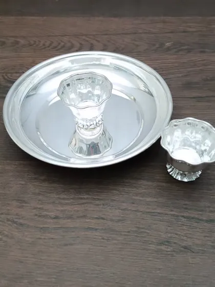 A simple German silver pooja set, containing a small plate, a diya, and a kumkum holder, perfect for a small altar or as a travel set.