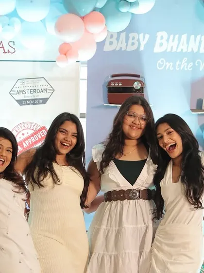 Friends having a blast at the travel-themed photo booth. The backdrop, with its visa stamp details and pastel balloons, was a popular spot for photos all day long.