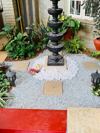 I love incorporating traditional elements into my garden designs. Here, we created a beautiful setting around a classic Deepa Stambha, using a mix of gravel, stepping stones, and shade-loving plants to make it the serene focal point of the entrance.