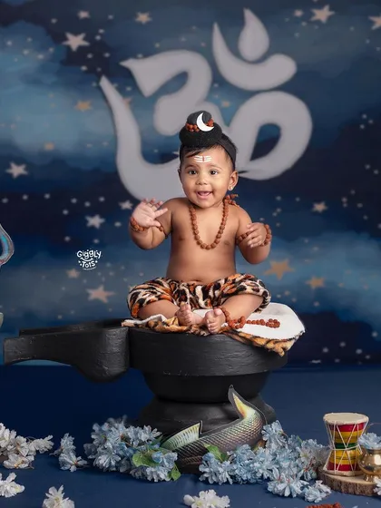 This happy baby Shiva is ready to play, sitting cheerfully on a shivling in our festive setup.