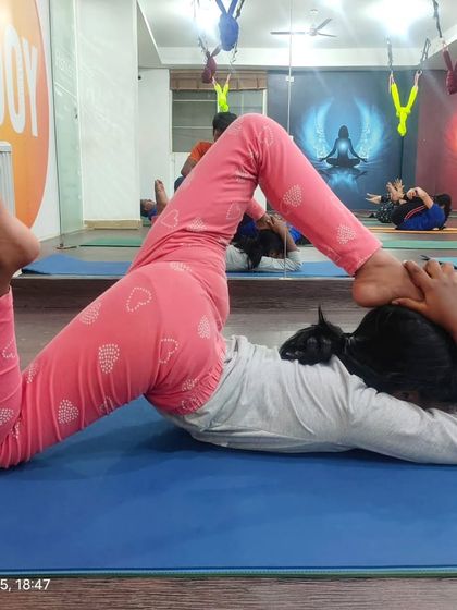 A young student practices Bhekasana, or Frog Pose, which is excellent for stretching the thighs and opening the hips. Each child works at their own pace to build flexibility over time.