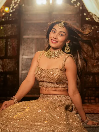 A smiling, candid-style shot from the golden lehenga series, showing the model's personality.