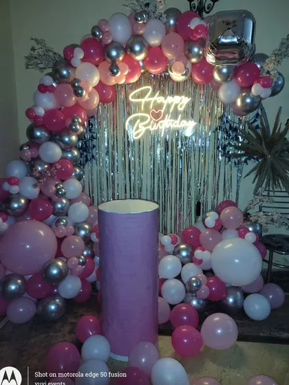 Another view of the pink and silver balloon arch against a silver fringe curtain.