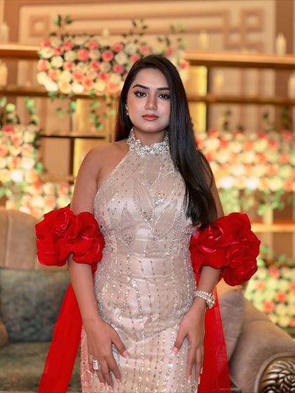 A full-length view of my beige and red gown against a floral backdrop. The halter neck and detailed silver embroidery add a touch of modern elegance.