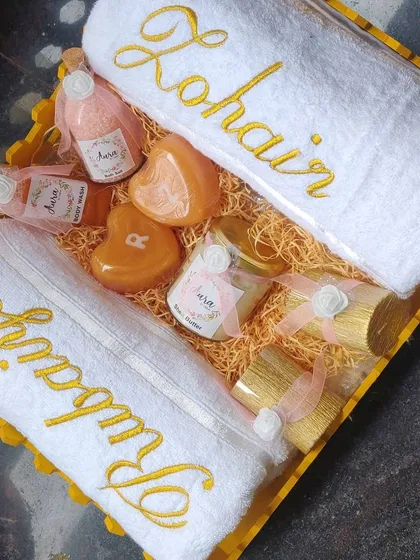 This golden-themed wedding hamper is one of my bestsellers. It includes personalized towels, heart-shaped initial soaps, Shea butter, body wash, and even luxury candles for a complete gift.