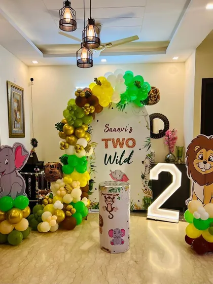 We transformed this living room into a "Two Wild" jungle safari for a second birthday party. This setup includes a personalized backdrop, a full balloon arch in jungle colors, cute animal cutouts of a lion and elephant, and a light-up number '2'.