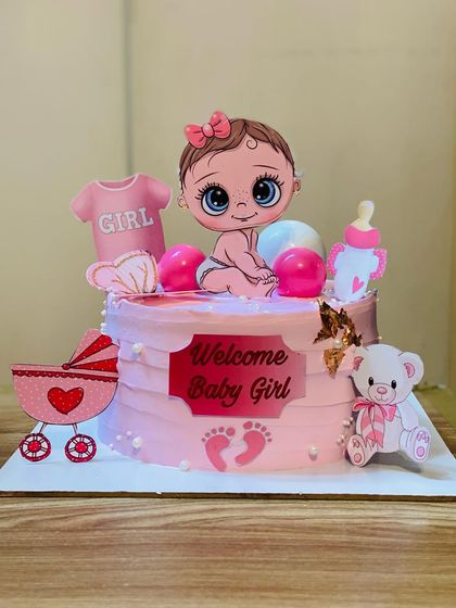 A sweet "Welcome Baby Girl" cake with adorable baby-themed toppers.