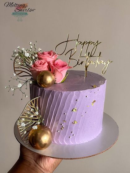 Pretty in purple! This Biscoff buttercream cake is decorated with fresh pink roses, baby's breath, and gold accents for a touch of glamour.