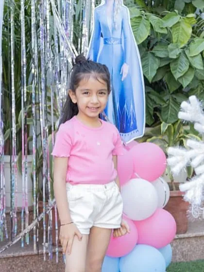 A happy little guest posing in front of our Elsa cutout and snowflake decorations. Creating these picture-perfect moments is what it's all about.