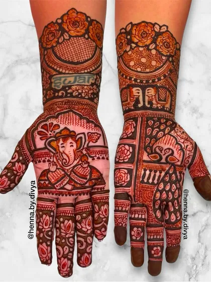 A divine bridal mehendi featuring a beautifully detailed portrait of Lord Ganesha on one palm. The other hand is adorned with a peacock and intricate floral and geometric patterns.