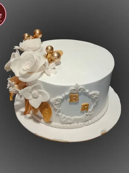 This elegant white and gold anniversary cake is adorned with handcrafted white sugar flowers. The custom monogram adds a personal touch to celebrate another year together.