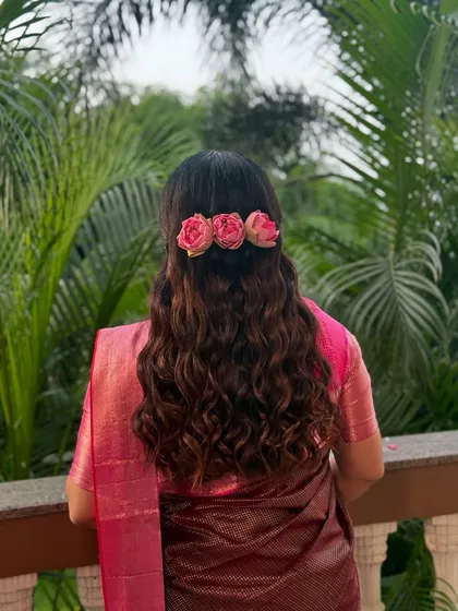 A simple yet elegant hairstyle with soft waves, adorned with three pink roses for a romantic touch.