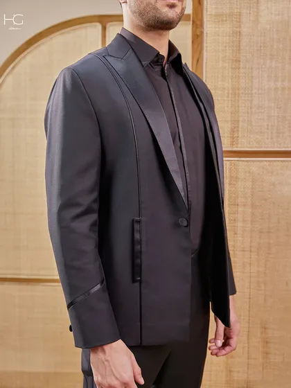 A closer view of the black suit that redefines presence, highlighting the unique, extended lapel design and the impeccable fit across the chest and shoulders.