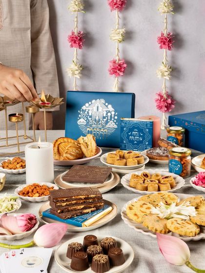 Lighting a diya over our festive spread. Our Meetha Maska collection is designed to encapsulate the traditions and joy of a Bombay Diwali.