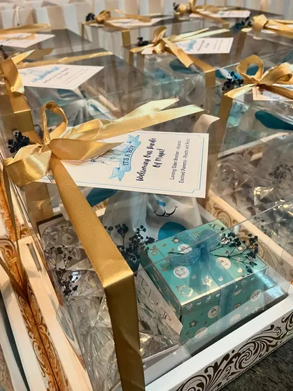Another angle of the baby announcement hampers, showing the elegant packaging with ornate wooden-style boxes and clear lids, all tied with beautiful gold ribbons.