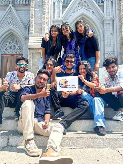 The group with our 'Let's Explore' sign on the steps of the cathedral. We are proud to bring people together to discover new places.