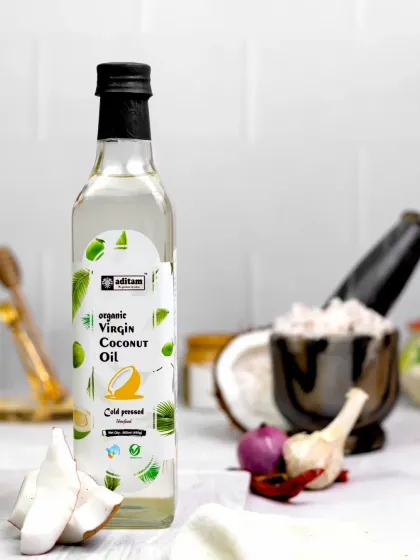 This shot of virgin coconut oil includes a mortar and pestle with fresh coconut and spices. The styling hints at its use in cooking, creating a fresh and authentic kitchen scene.