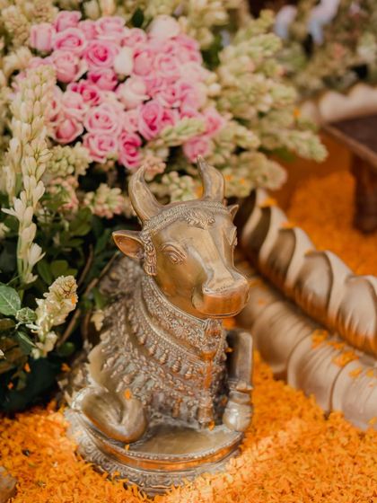 A close-up of a traditional brass Nandi statue, adorned with flowers as part of a divine mandap setup. We incorporate authentic cultural elements to create a meaningful and sacred atmosphere.