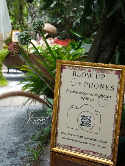 A closer look at the "Blow Up Our Phones" sign, a modern and fun way to collect memories from guests.