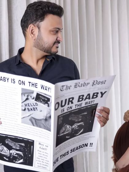 A playful take on the pregnancy announcement. The dad-to-be reads the "news" while the mom-to-be looks on with a smile.