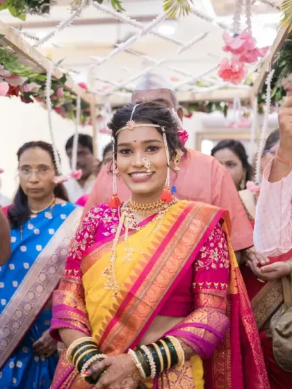 The radiant Maharashtrian bride makes her entrance, walking under a floral canopy held by her brothers, her smile filled with anticipation.