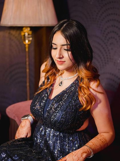 A seated portrait in a sparkling navy blue gown by Seema Gujral. This shot highlights the intricate details and the glamour of the dress.