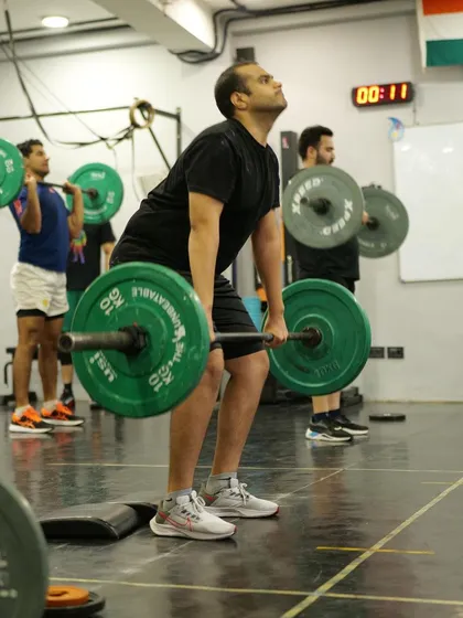 A class in sync during a weightlifting session. Everyone is focused on their own barbell, but the collective energy in the room is what pushes each person to complete that next rep with good form.