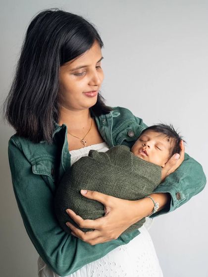 A mother gazes lovingly at her swaddled newborn. These simple, heartfelt portraits are often the ones parents cherish the most.