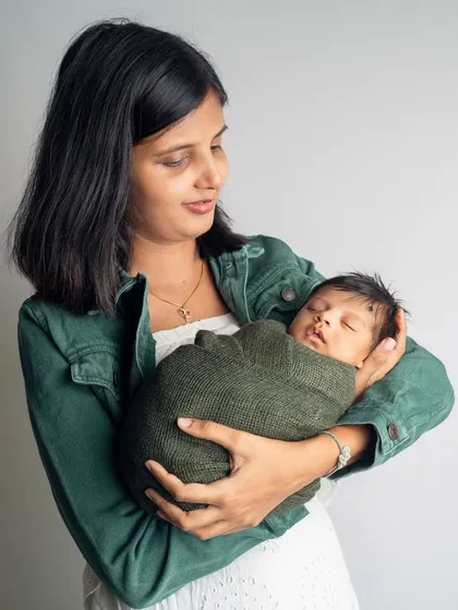 A mother gazes lovingly at her swaddled newborn. These simple, heartfelt portraits are often the ones parents cherish the most.