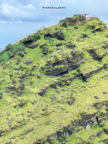 A close-up of the rocky, green peak of Deviramma Betta in Chikmagalur, a site of a unique annual festival.