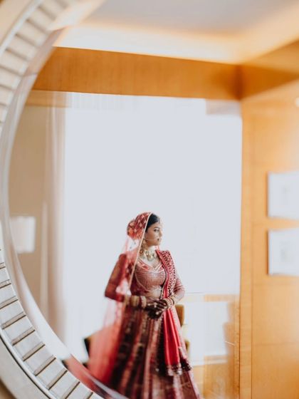 A creative bridal portrait using a mirror to frame the bride, Eesha, adding depth and a unique perspective.