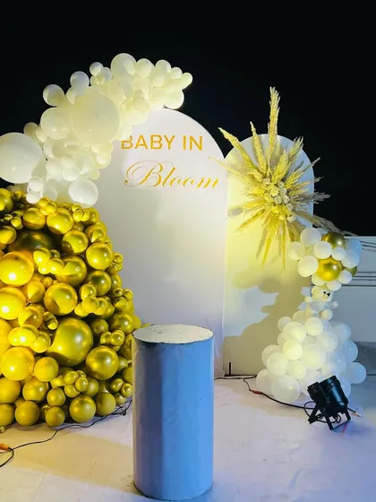 An elegant "Baby in Bloom" baby shower theme, perfect for a modern celebration. This design uses a clean white arched backdrop, a cascade of metallic gold and white balloons, and a stylish dried pampas grass arrangement for a sophisticated look.