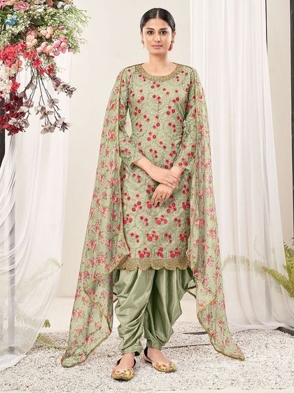 This pista green net suit is fresh and floral. The thread embroidery and printed dupatta with dhoti pants create a playful yet elegant look.