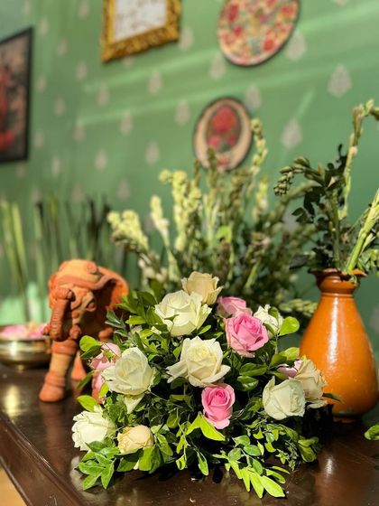 The soft colors of the roses contrast beautifully with the rustic terracotta vase and elephant figurine.