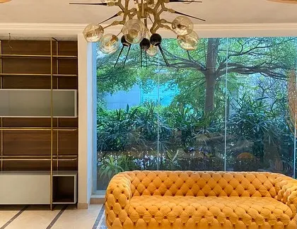 A breathtaking living room view, featuring our vibrant tufted yellow sofa and a custom-built bookshelf that frames a picturesque window.