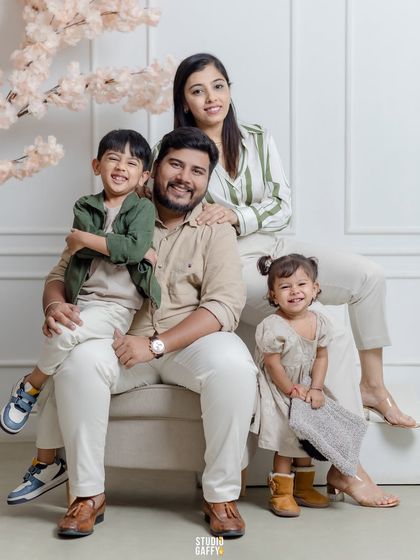 A lovely portrait of a family of four, with smiles all around. The coordinated neutral outfits and soft lighting create a warm and inviting feel.