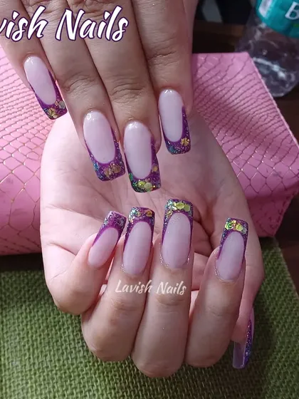 A bold, square-tipped French manicure with chunky, multi-colored purple glitter.