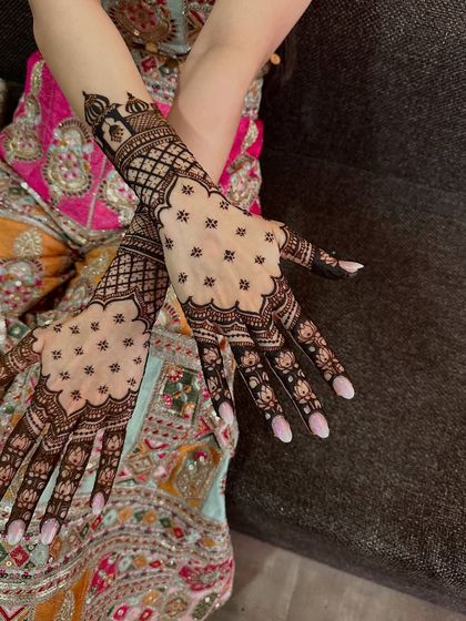 This elegant design uses negative space beautifully, with a delicate jaali or net pattern on the back of the hands. The fingertips are detailed with lotus buds.